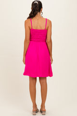 woman wearing a bright pink spaghetti strap sundress with a smocked bodice and a flared skirt, viewed from the back