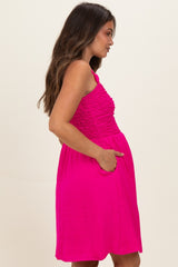 woman wearing a bright pink maternity dress with smocked bodice and pockets, showing her baby bump from the side