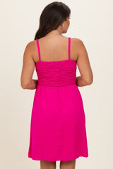woman wearing a vibrant pink maternity dress with a smocked bodice and adjustable spaghetti straps, viewed from the back