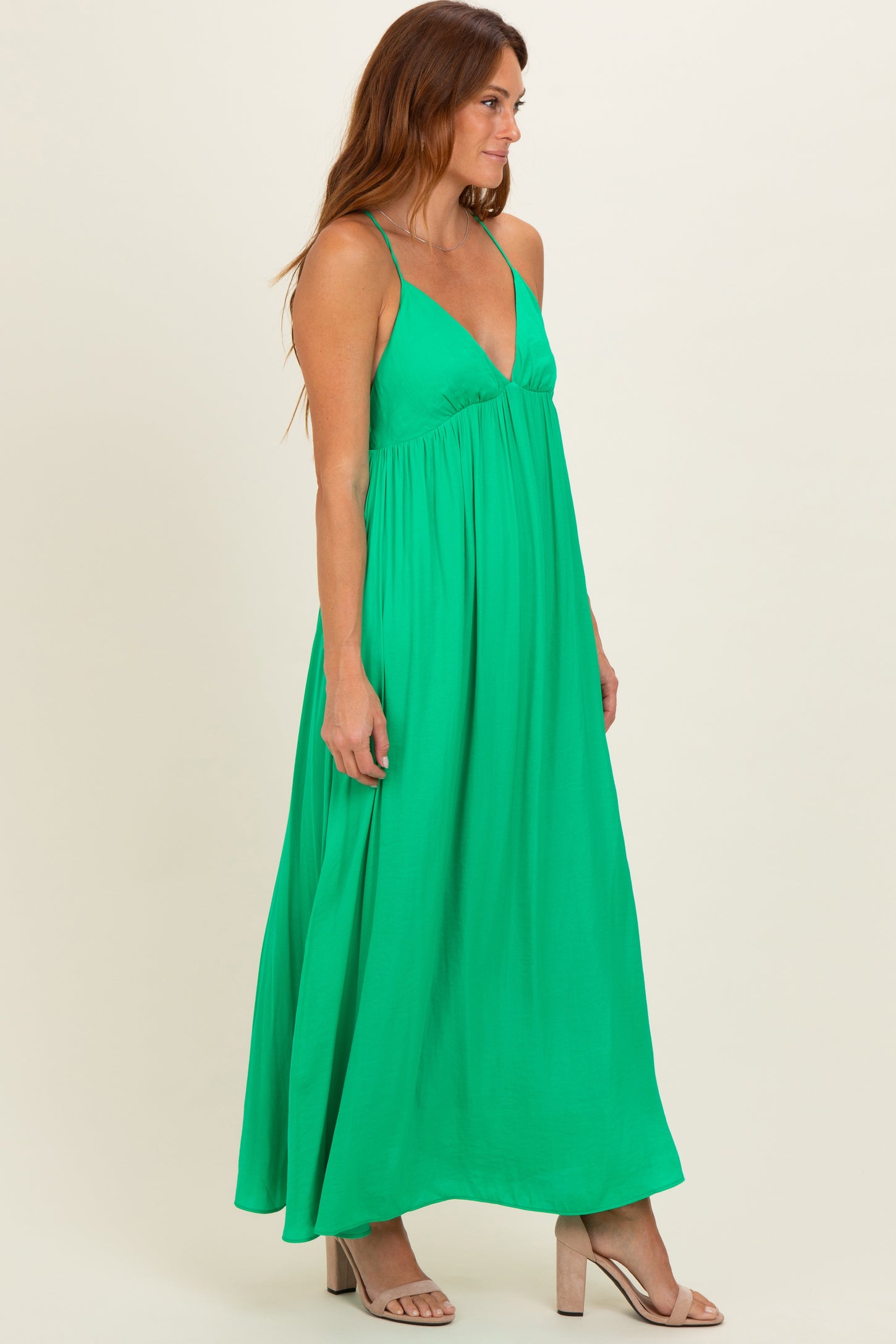 woman wearing a bright green sleeveless maxi dress with a flowy silhouette and a deep v-neckline