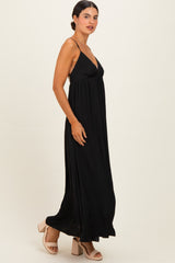 woman wearing a black maxi dress with spaghetti straps and a flowing silhouette standing in profile