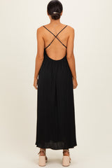 woman wearing a black backless maxi dress with crisscross straps and a flowy silhouette