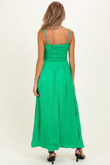 woman wearing a green maternity maxi dress with smocked bodice and spaghetti straps, showing a baby bump from the back