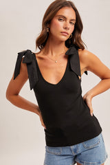 woman wearing a black ribbed tank top with bow tie straps and styled with denim shorts