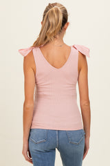 woman wearing a light pink ribbed maternity tank top with bow tie shoulder details, back view