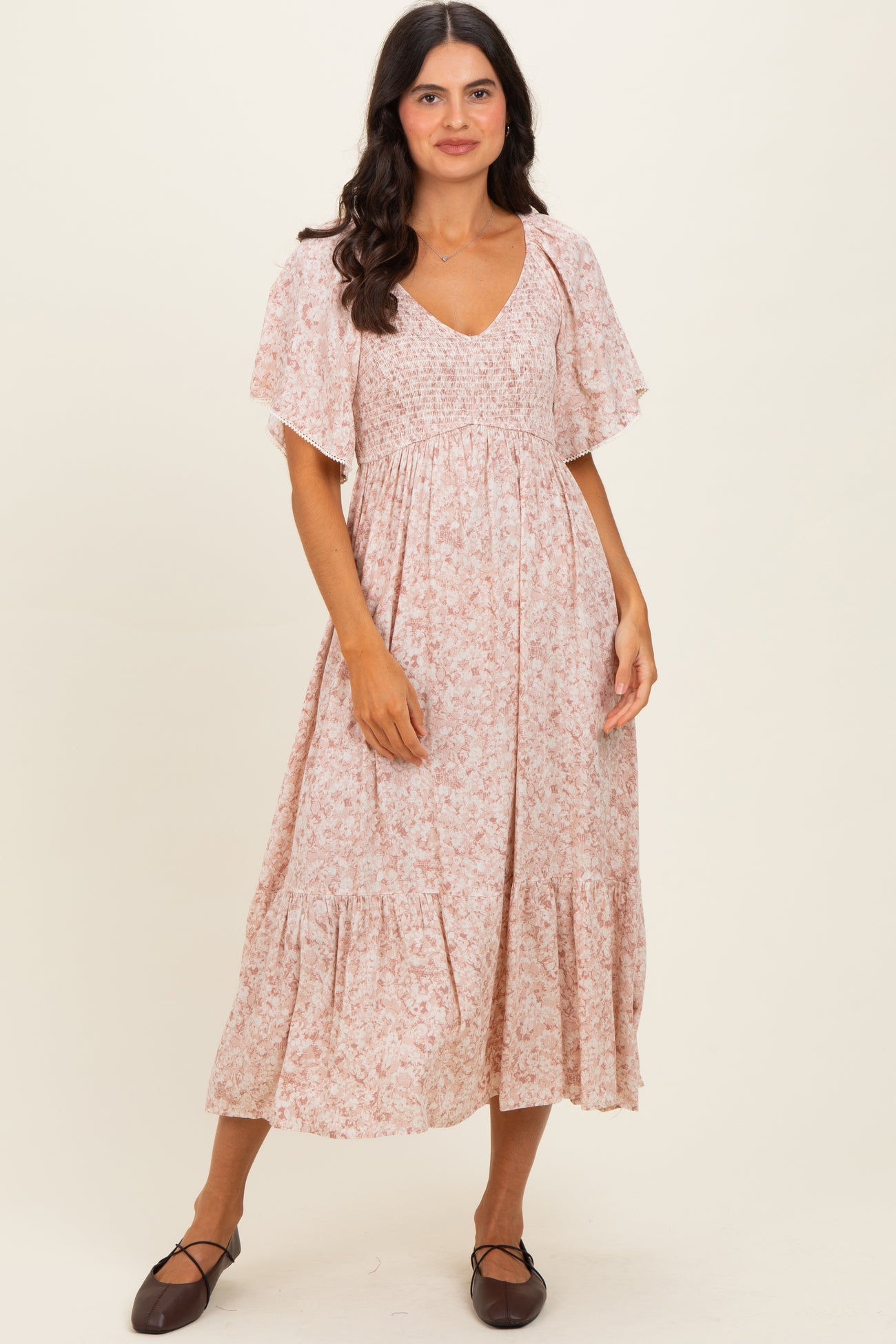 woman wearing a light pink floral maxi dress with short flutter sleeves and a smocked bodice