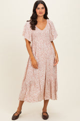 woman wearing a light pink floral maxi dress with short flutter sleeves and a smocked bodice