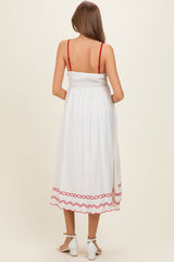 woman wearing a white maternity dress with red trim and adjustable straps, showing a baby bump from the back