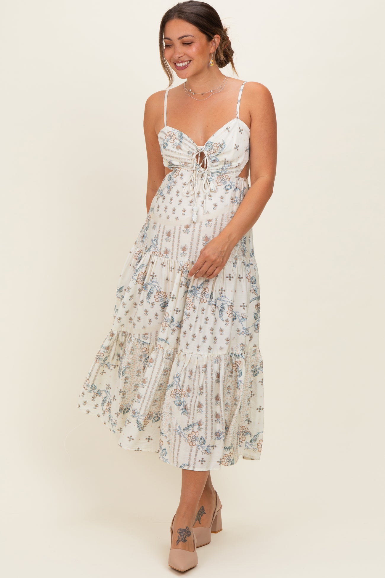 woman wearing a floral print maternity dress with a tie front and tiered skirt, showcasing her baby bump