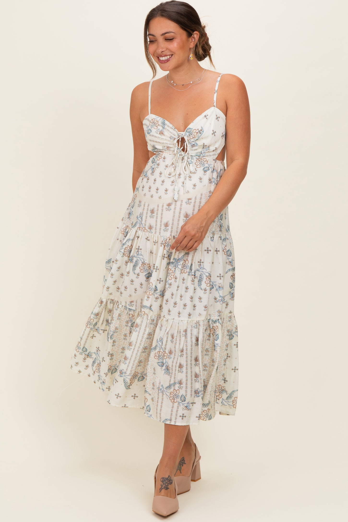 woman wearing a floral print maternity dress with a tie front and tiered skirt, showcasing her baby bump