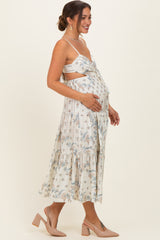woman wearing a cream floral maternity maxi dress, showing her baby bump with a side profile pose
