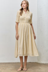 woman wearing a light beige button-up midi dress with smocked bodice and short sleeves