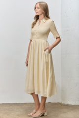 woman wearing a cream short sleeve button-up dress with a smocked bodice and pockets, standing against a neutral background