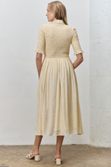 woman wearing a cream-colored smocked midi dress with short sleeves, shown from the back