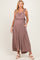 woman wearing a mauve maternity jumpsuit with ruffled straps and pockets, showing her baby bump