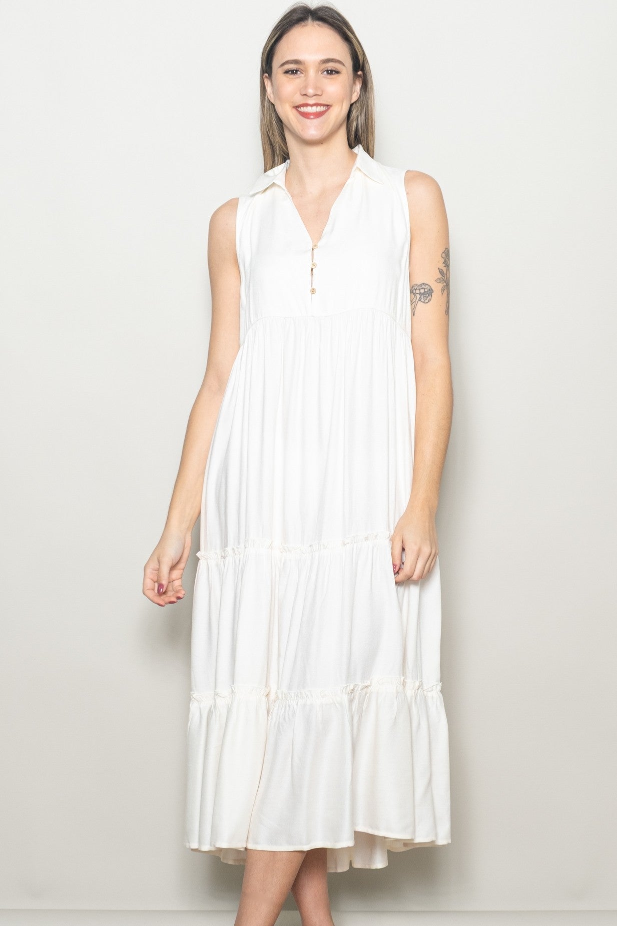 woman wearing a sleeveless white midi dress with a collar and tiered ruffle details