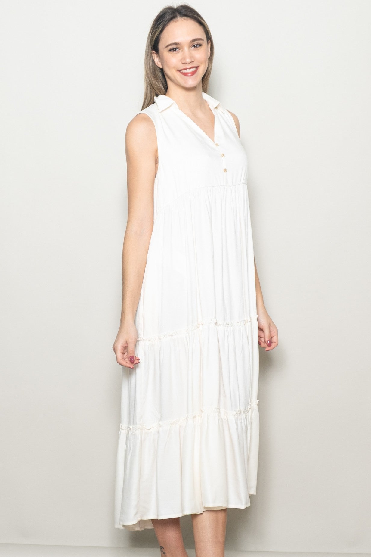 woman wearing a sleeveless white tiered midi dress with a collar and buttons