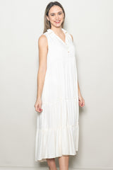 woman wearing a sleeveless white tiered midi dress with a collar and buttons
