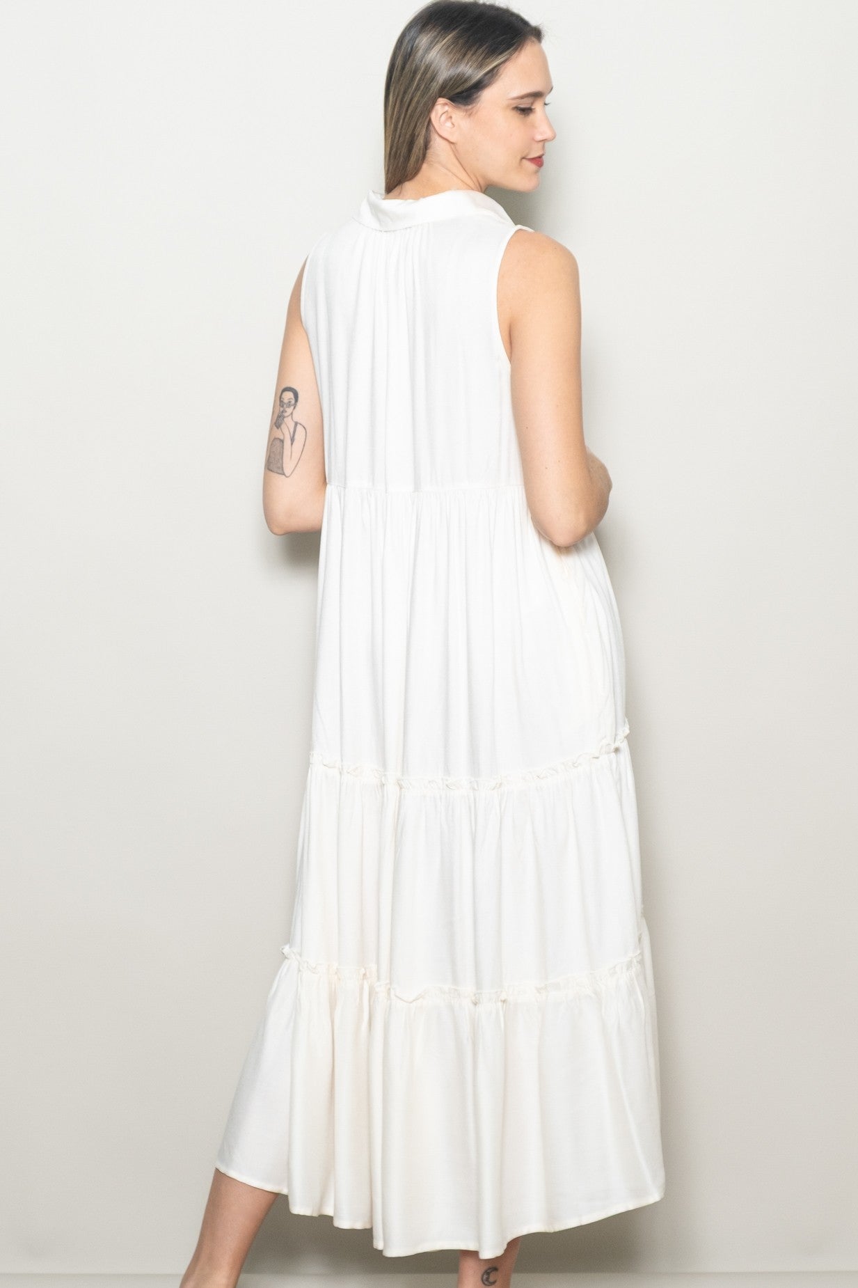 woman wearing a white sleeveless midi dress with a tiered design and relaxed fit, showing the back view