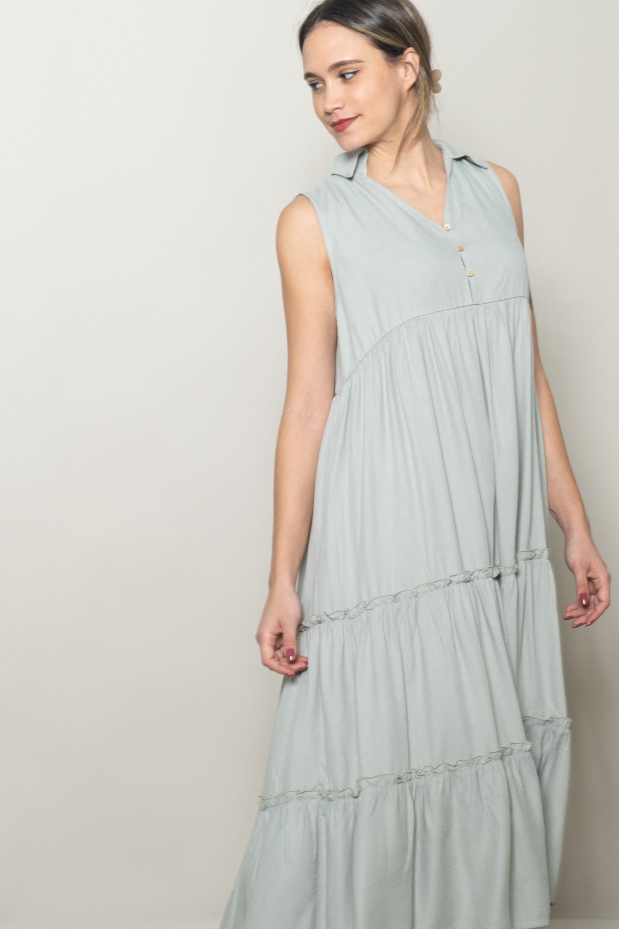woman wearing a light green sleeveless maxi dress with a button-down collar and tiered ruffle details
