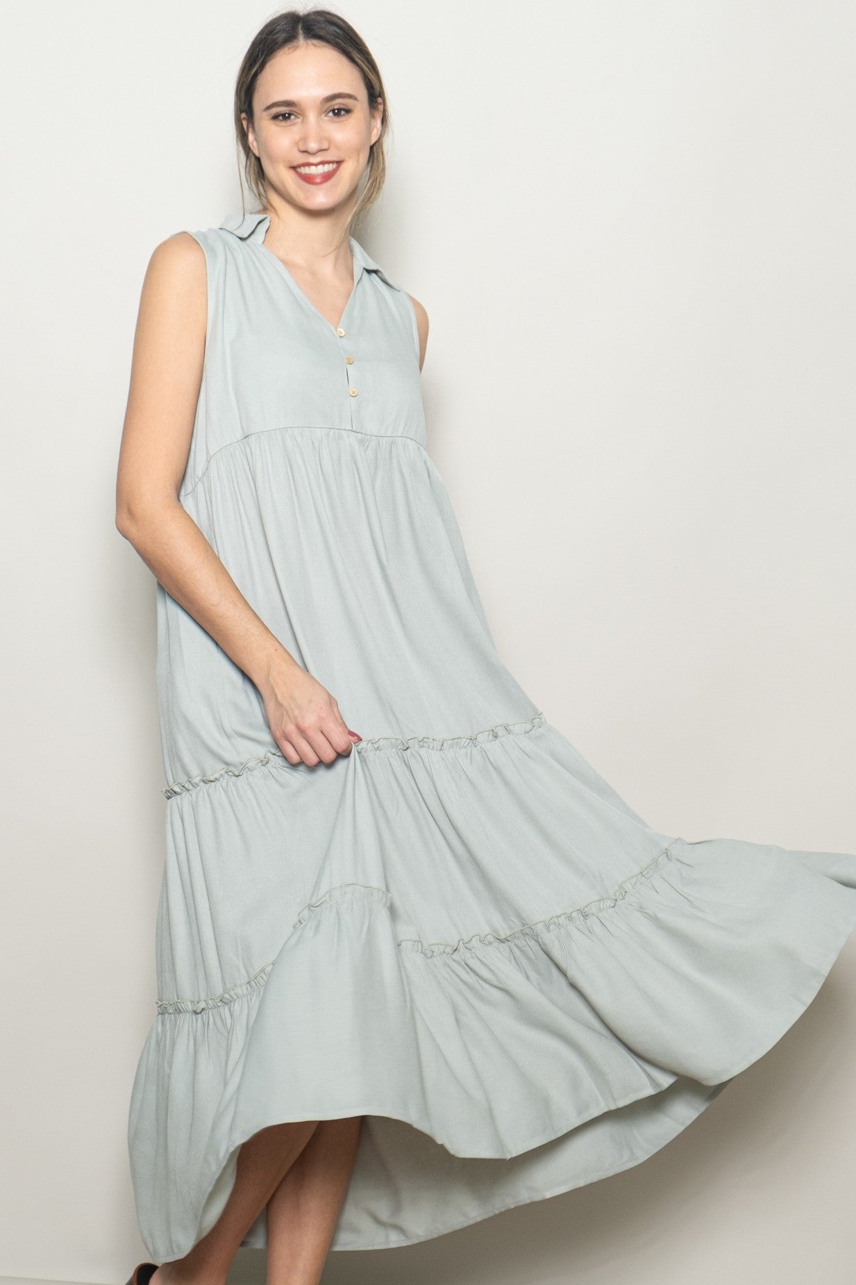 woman wearing a light green sleeveless tiered maxi dress with a collar and button detail