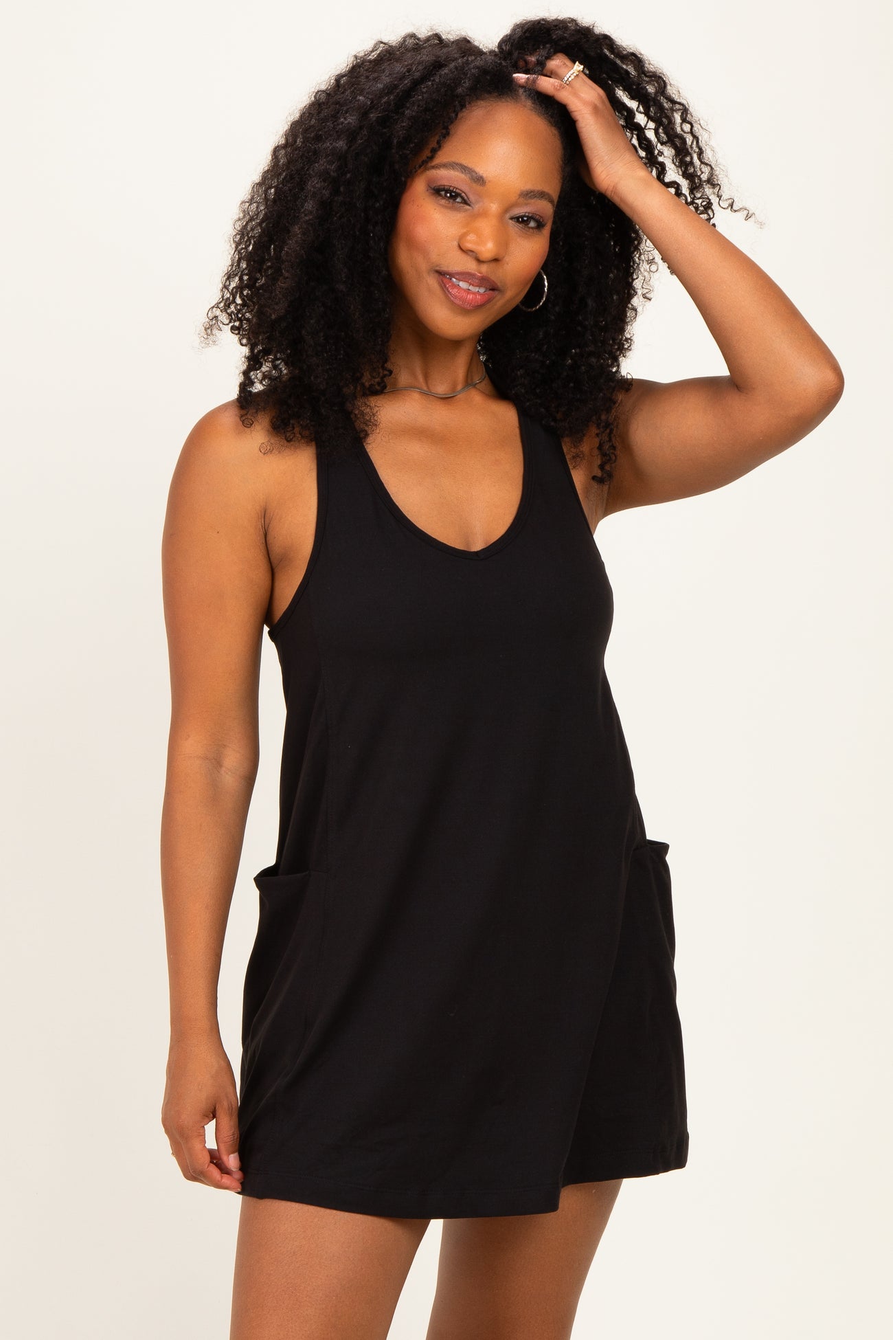woman wearing a black sleeveless romper with side pockets and a relaxed fit
