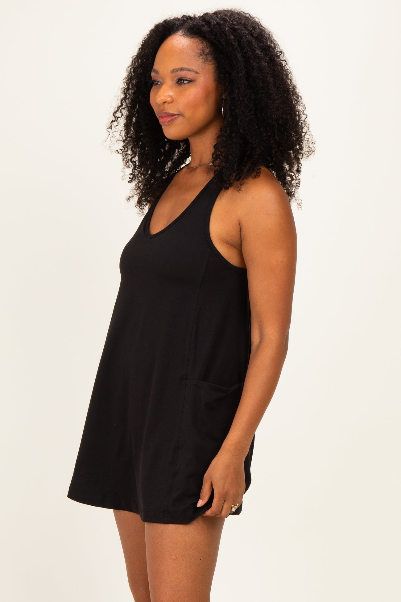 woman wearing a black sleeveless casual dress with pockets and a V-neckline