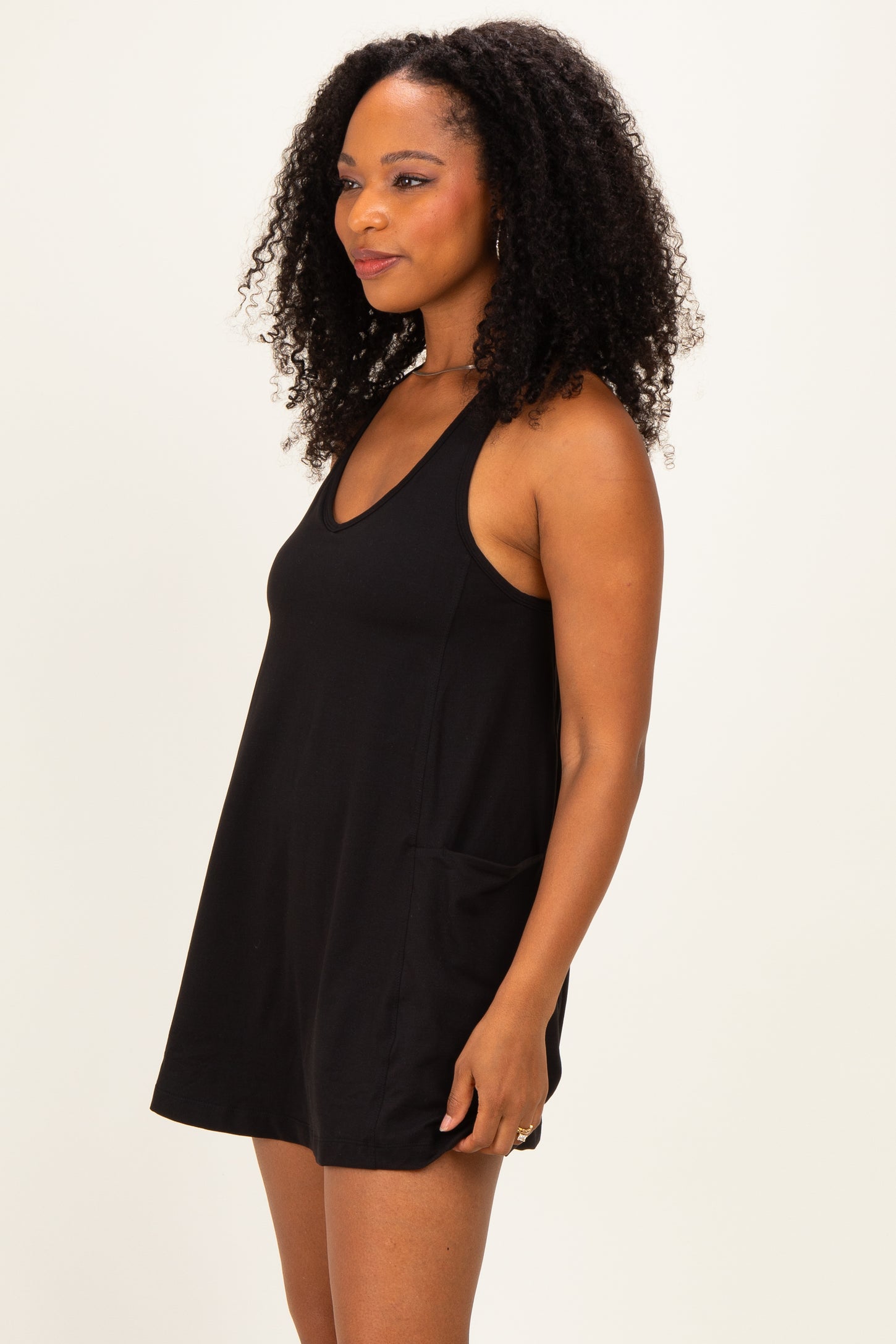woman wearing a black sleeveless casual dress with pockets and a V-neckline