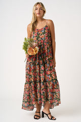 woman wearing a floral maxi dress with a tiered design and holding a bouquet of flowers