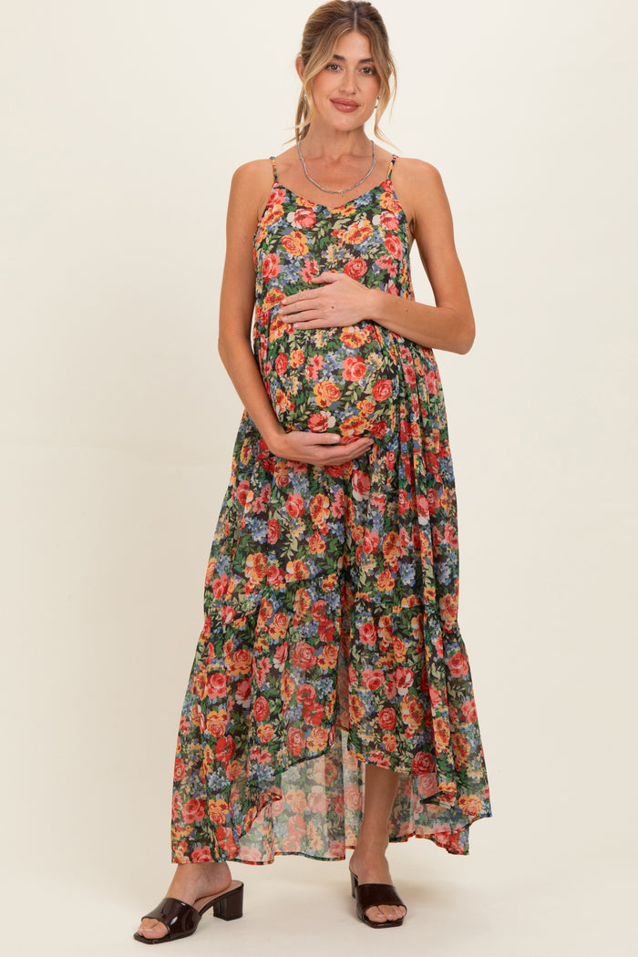 woman wearing a floral maternity maxi dress with a ruffled hem and holding her baby bump