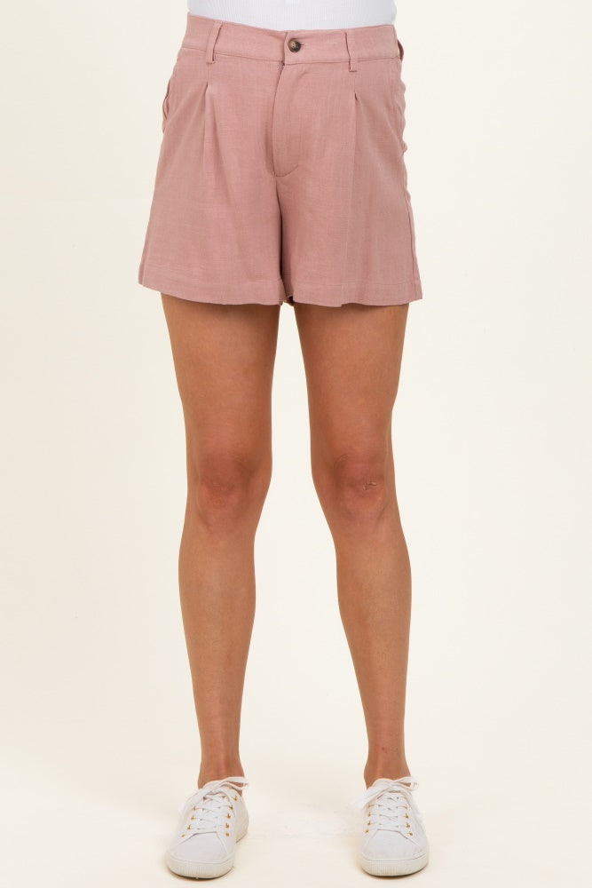 woman wearing pink tailored maternity shorts with pleat details and white sneakers