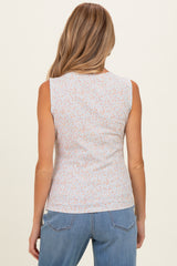 woman wearing a light blue sleeveless maternity top with a floral print, facing away from the camera
