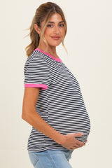 woman wearing a black and white striped maternity top with pink trim, showing her baby bump while smiling