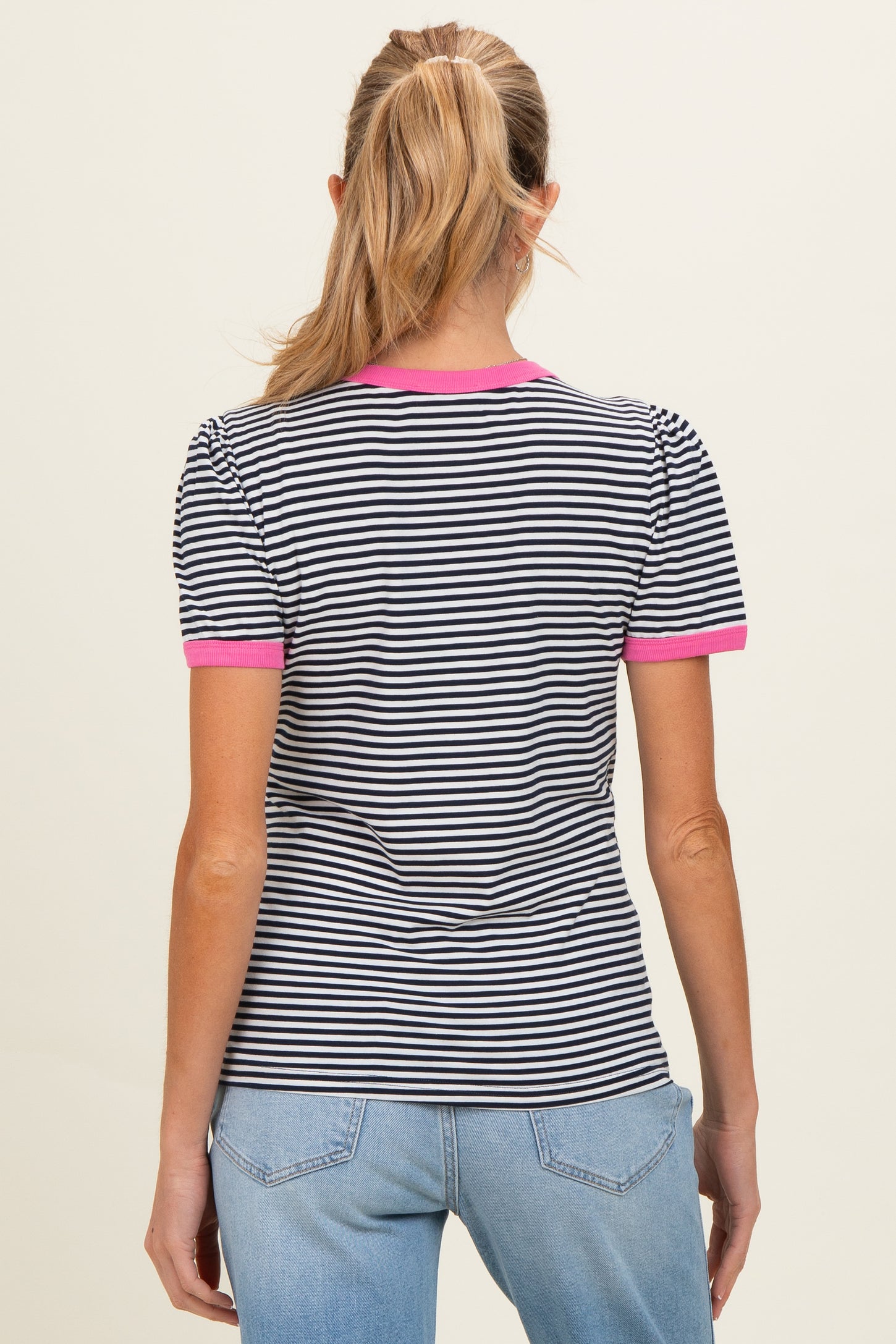 woman wearing a black and white striped maternity top with pink trim on the sleeves and neckline