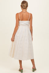 woman wearing a white sleeveless maternity dress with a pleated skirt, showing her back