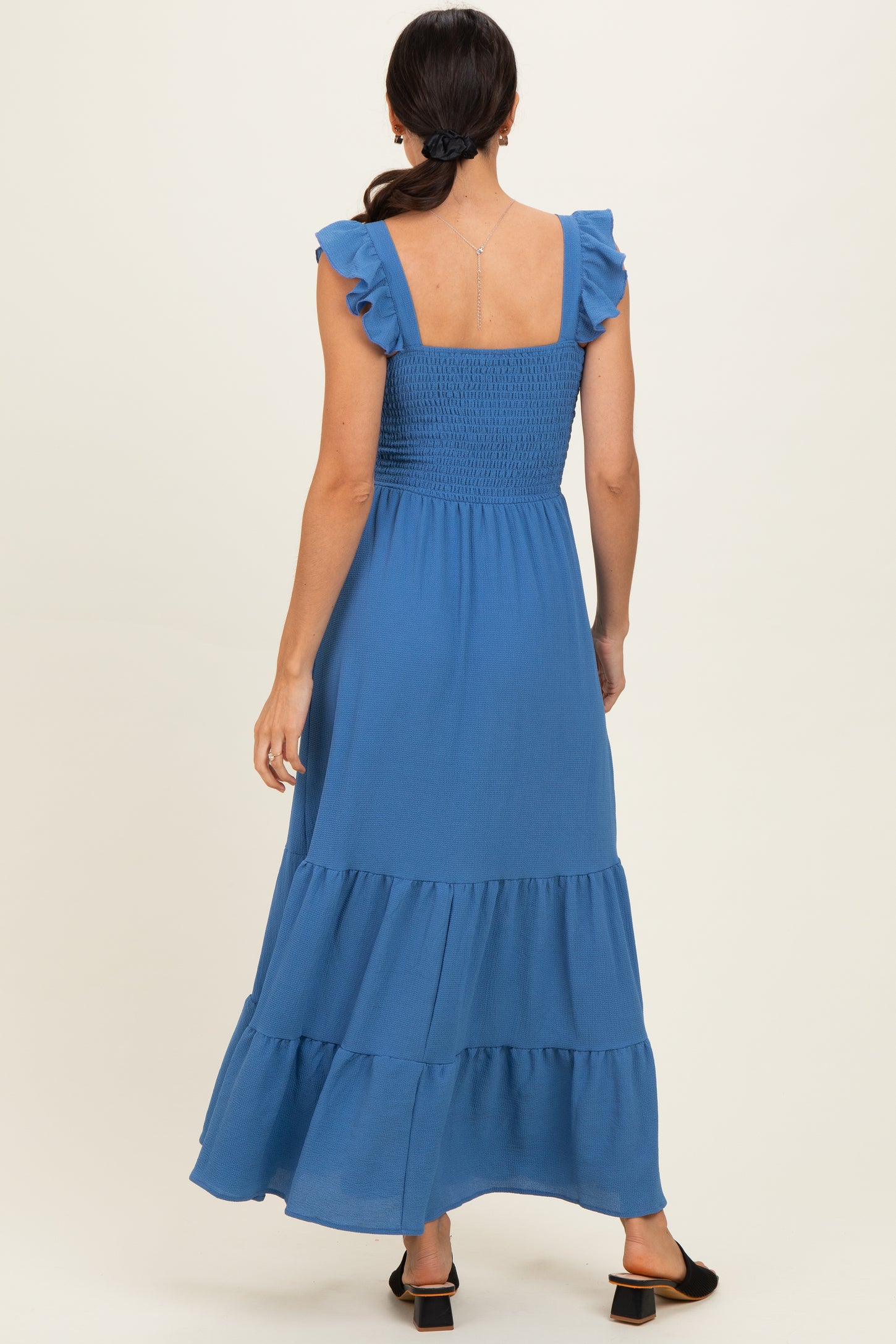 woman wearing a blue tiered maxi dress with ruffle sleeves and a smocked back