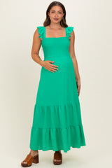 woman wearing a bright green maternity maxi dress with ruffle sleeves and a smocked bodice, showing her baby bump