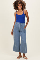woman wearing a blue maternity tank top and light blue wide-leg maternity pants with pockets and drawstring waistband