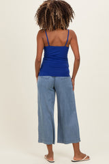woman wearing a blue maternity tank top and light blue wide-leg jeans, seen from the back