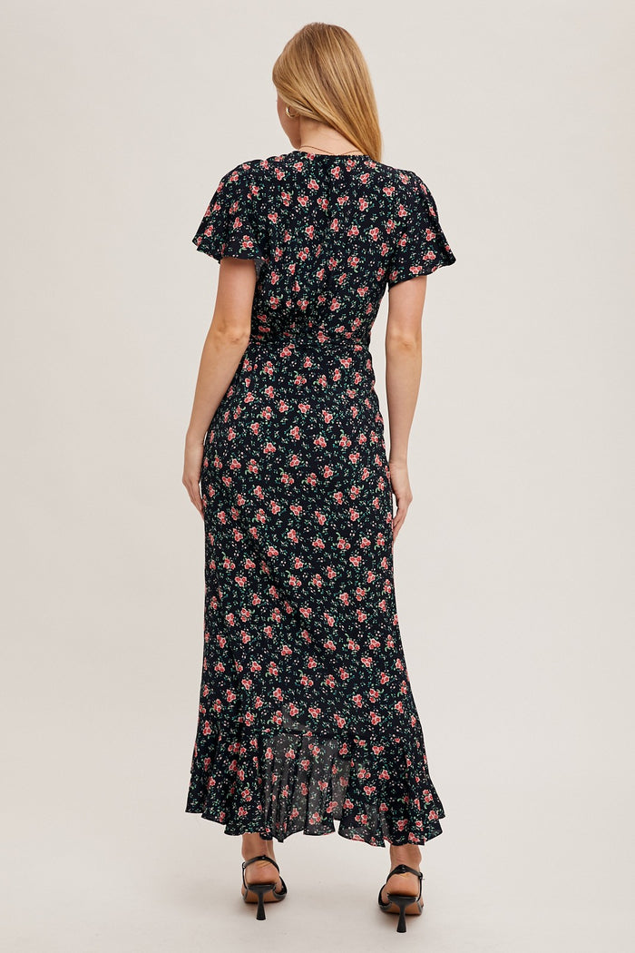 woman wearing a black floral maxi dress with short flutter sleeves and a ruffled hem