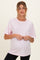 woman wearing a light pink short sleeve maternity top and holding her baby bump