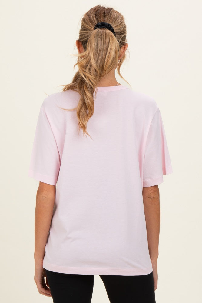 woman wearing a light pink oversized maternity t-shirt, showing the back with a relaxed fit