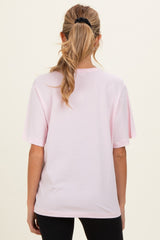 woman wearing a light pink oversized maternity t-shirt, showing the back with a relaxed fit