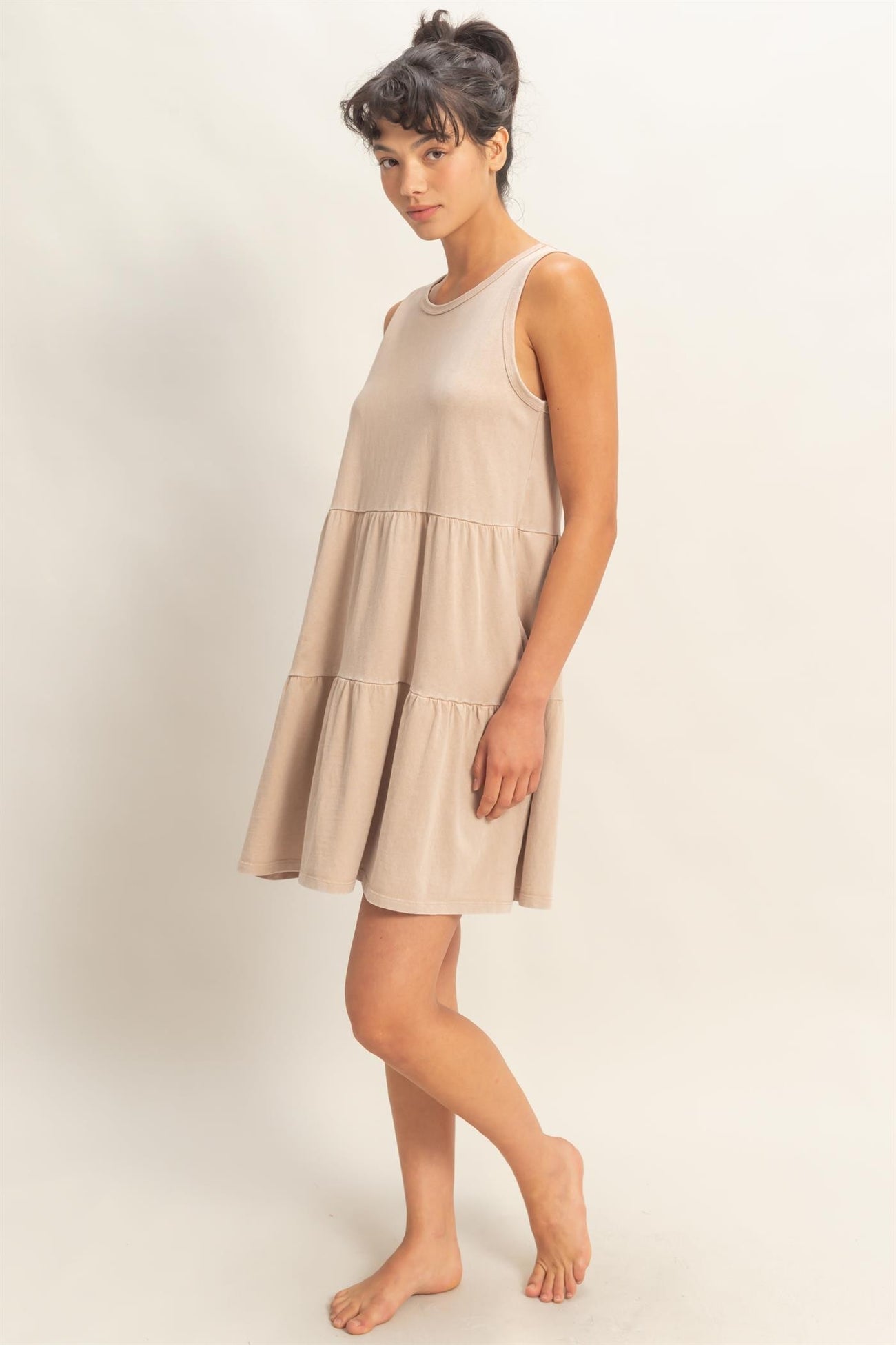 woman wearing a beige tiered tank dress with a relaxed fit and a flared hem