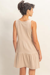 woman wearing a beige sleeveless tiered dress with a relaxed fit, viewed from the back
