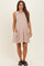 woman wearing a light brown sleeveless maternity dress with a tiered design and pockets