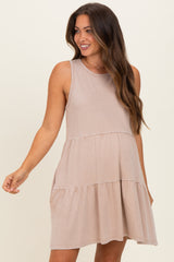 woman wearing a tan sleeveless maternity dress with a tiered skirt detail and a relaxed fit
