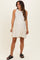 woman wearing a creamy white sleeveless maternity dress with tiered design and black sandals