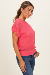 woman wearing a bright pink short sleeve knit sweater paired with blue jeans, showing a relaxed fit