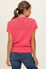 woman wearing a pink short sleeve knitted sweater with a loose fit and a rounded neckline, paired with jeans